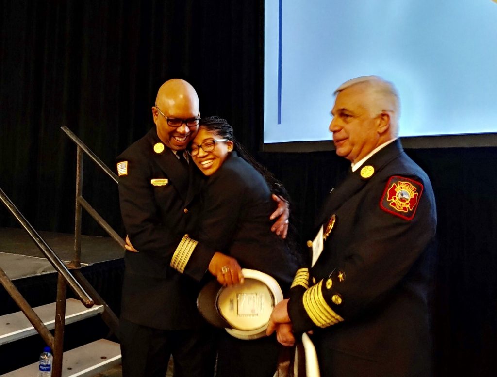 Ardavia Lee, daughter of a fallen Wilmington firefighter, is embraced by members of the fire department after receiving a $25,000 scholarship. (Zoe Read/WHYY)