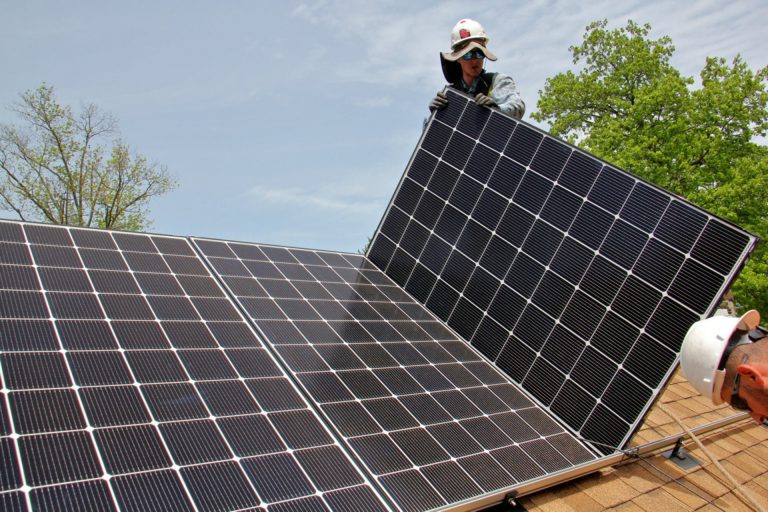Patrick Whittaker of Solar States installs solar panels on the roof of a home in Bryn Mawr.