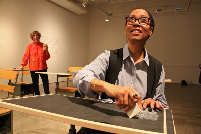 Sonya Clark makes a chalk rubbing of the Confederate truce flag, an activity available to visitors to her exhibit at the Fabric Workshop and Museum. (Emma Lee/WHYY)