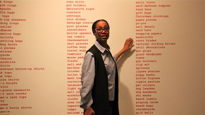 Sonya Clark gestures to a list of the many things available for purchase decorated with the Confederate battle flag. (Emma Lee/WHYY)
