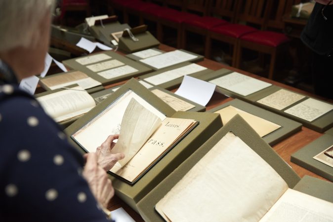 Lynne Farrington, Project Director of Whitman at 200, carefully turns a page in an early edition of Walt Whitman's Leaves of Grass. (Natalie Piserchio for WHYY)