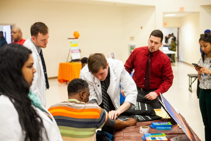 Medical students from University of the Sciences perform blood pressure tests at the 2019 Men's Health Iniative at Enon Tabernacle Baptist Church. (Brad Larrison for WHYY)