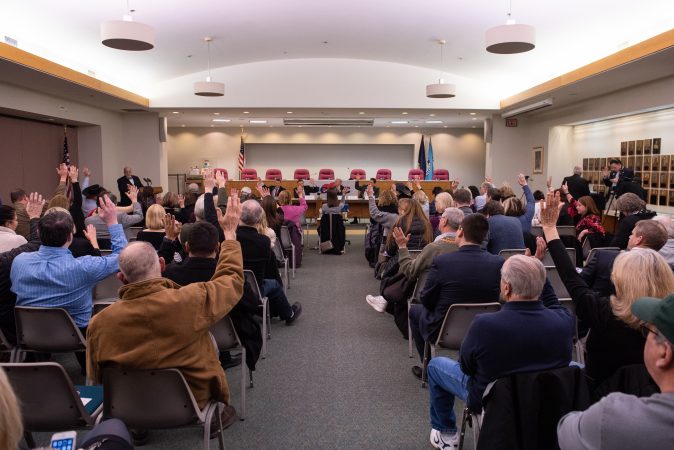 Attendees raise their hand in support of a list of traditionally conservative values prior to the start of a debate between Republican candidates for Montgomery County commissioner held at the Upper Merion Township Building in King of Prussia, Pa. on Thursday, February 28, 2019. (Kriston Jae Bethel for WHYY)