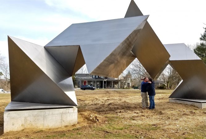 Woodmere Museum Director William Valerio (right) hugs museum Board President James Alexandre under the newly relocated sculpture, 