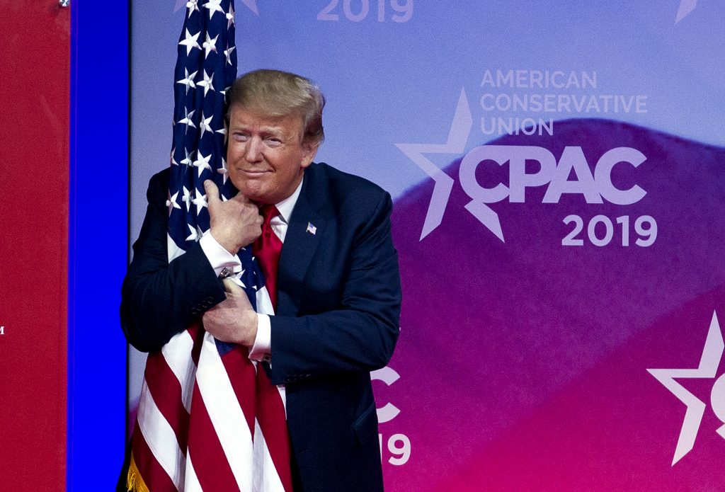Trump President Donald Trump hugs the American flag as he arrives to speak at Conservative Political Action Conference, CPAC 2019, in Oxon Hill, Md., Saturday, March 2, 2019. (AP Photo/Jose Luis Magana)