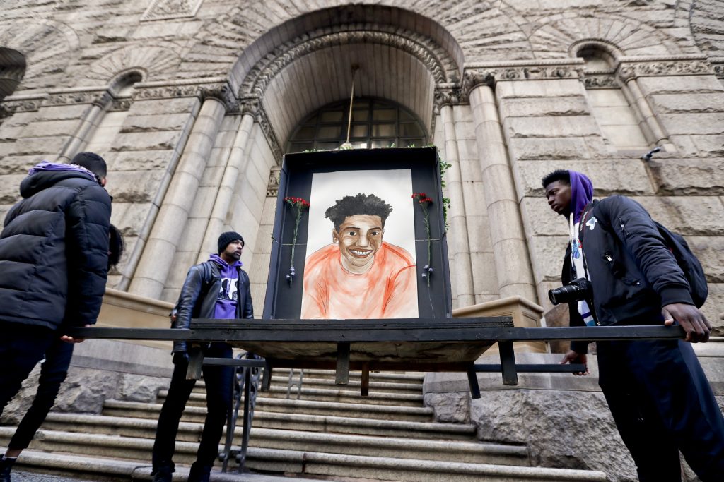 Farooq Al-Said, Jasiri X, Jarrion Manning Farooq Al-Said, left, Jasiri X, center, and Jarrion Manning, right, hold a memorial display with a drawing of Antwon Rose II in front of the court house on the first day of the trial for Michael Rosfeld, a former police officer in East Pittsburgh, Pa., begins on Tuesday, March 19, 2019, in Pittsburgh. (Keith Srakocic/AP Photo)