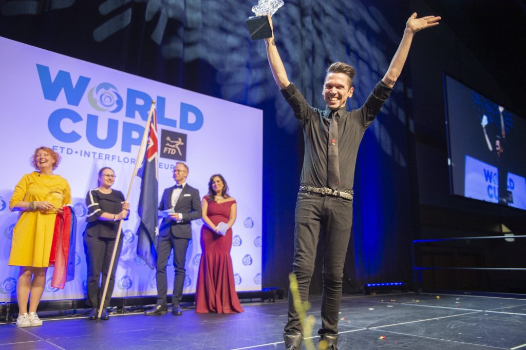 FTD WORLD CUP Declared the winner of the FTD Interflora World Cup Australia's Bart Hassam holds his trophy aloft and waves to the audience. (Jonathan Wilson for WHYY)