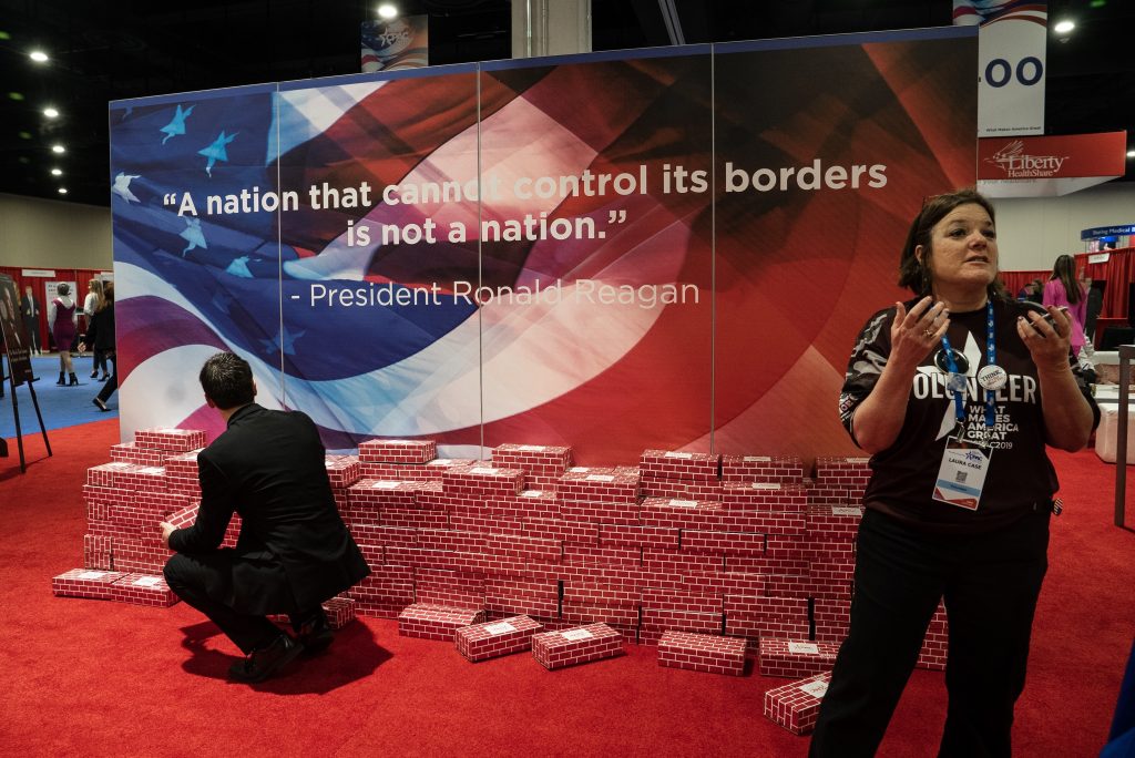 A fake wall, made of cardboard bricks, is on display with a quote by former president Ronald Reagan that reads: “A nation that cannot control its borders is not a nation.” A fake wall, made of cardboard bricks, is on display with a quote by former president Ronald Reagan that reads: