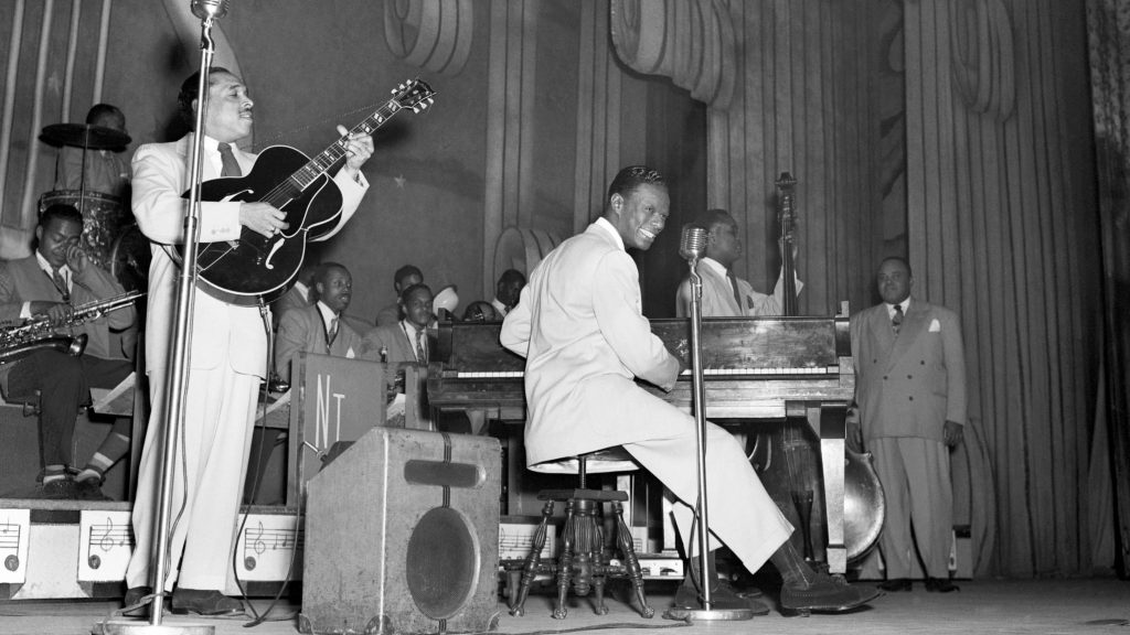 Nat King Cole plays with his jazz orchestra on the stage of The Apollo Theater, in Harlem, N.Y. in the 1950s. Nat 'King' Cole having a smoke while disembarking from a plane in 1963. (Evening Standard/Getty Images)