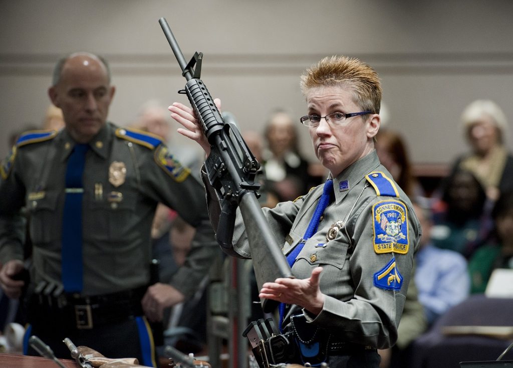 Detective Barbara J. Mattson, of the Connecticut State Police, holds up a Bushmaster AR-15 rifle, the same make and model of gun used by Adam Lanza in the Sandy Hook School shooting. (AP Photo/Jessica Hill, File)