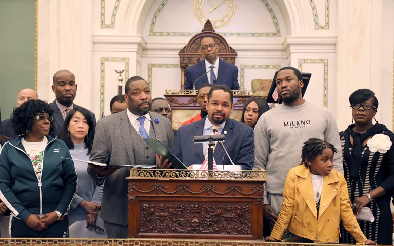 Meek Mill (right) and his son listen as Pennsylvania state Sen. Sharif Street (center) presents a state resolution in his honor. (Tom MacDonald/WHYY)