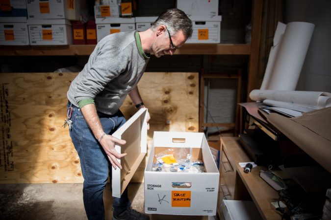 J.J. Tiziou opens up a box of space chotskies his father, French journalist Jacques Tiziou, left his as part of a massive collection of memorabilia from the space program. (Lindsay Lazarski/WHYY)