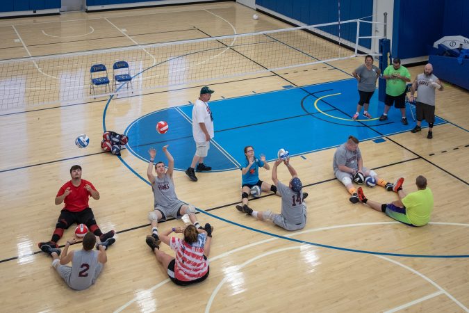 People practicing volleyball, while all are sitting on the floor
