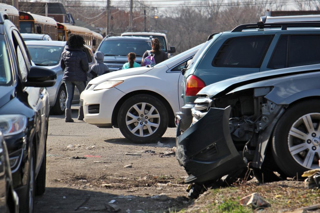 2019 03 18-e lee-west philadelphia-auto shops Students from Southwest Leadership Academy are seen in this 2019 file photo navigating a sidewalk near the school congested with wrecked cars and debris associated with two auto repair shops on the block. (Emma Lee/WHYY)