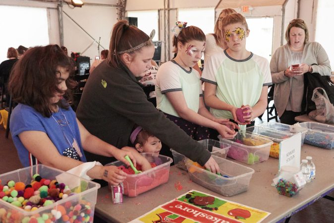 A sensory station is set up at Autism Awareness day at the Philadelphia Zoo, which includes kinetic sand bins, multi-colored pom poms, and small toys. (Natalie Piserchio for WHYY)