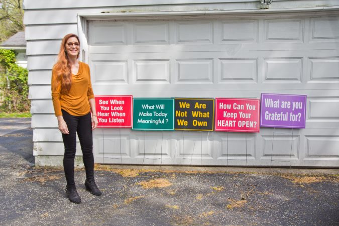 Meg Miller, a Lower Merion resident, with a few of her favorite signs that she displays on her property. (Kimberly Paynter/WHYY)