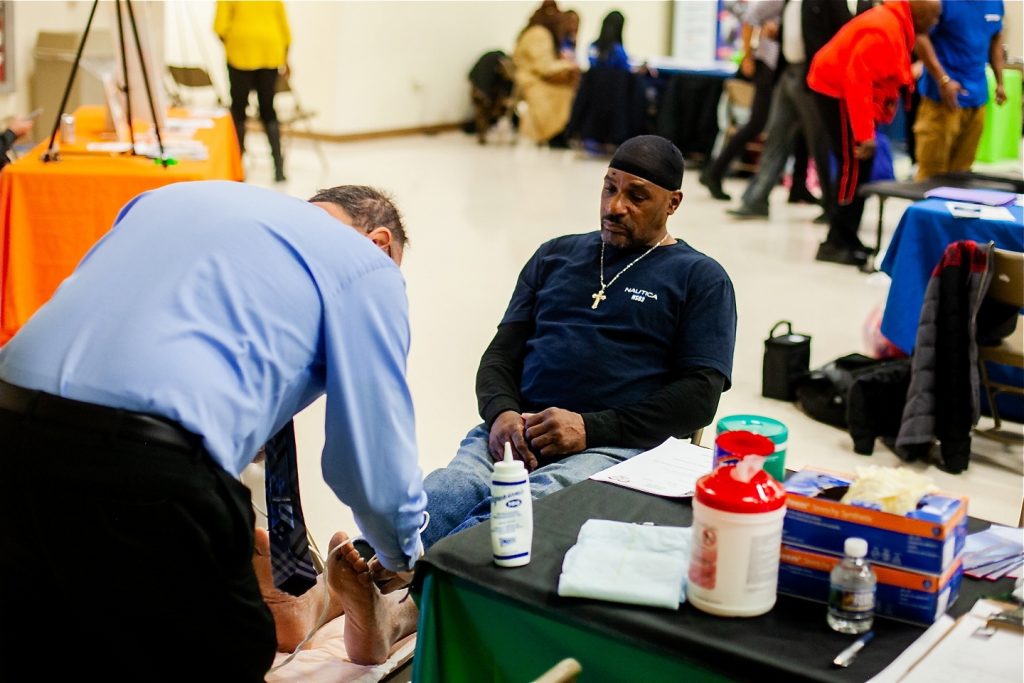 Dr. Ronald Renzi performs an ultrasound on Russell Davis to check on blood circulation in screenings for peripheral vascular disease during a health and wellness clinic at Enon Tabernacle Baptist Church in Mount Airy. (Brad Larrison for WHYY)