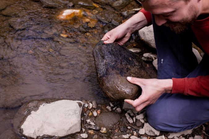 Entomologist Doug Sponsler looks under rocks for wildlife during the City Nature Challenge Sunday. (Brad Larrison for WHYY)