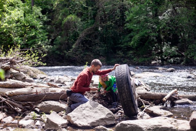 Entomologist Doug Sponsler and his daughter Ellie look for wildlife under an abandoned tire during City Nature Challenge Sunday. (Brad Larrison for WHYY)