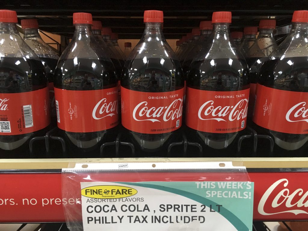Philadelphia Soda Tax A sweetened beverage tax sign is seen below a row of Coca Cola bottles