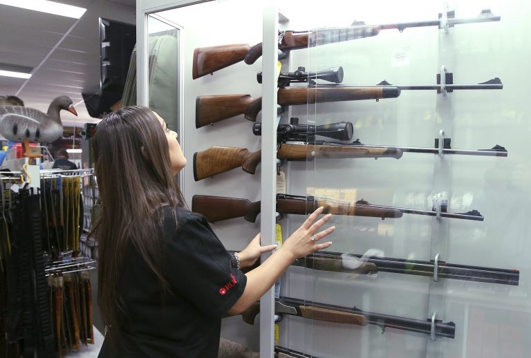 In this Wednesday, Oct. 4, 2017 file photo, a salesperson checks rifles in a gun shop display in Sydney, Australia. A documentary aired in March 2019 by Al Jazeera reported officials with Australia's far-right One Nation party met with two National Rifle Association representatives and other gun-rights advocates seeking money to undermine Australian gun laws. (Rick Rycroft/AP Photo)