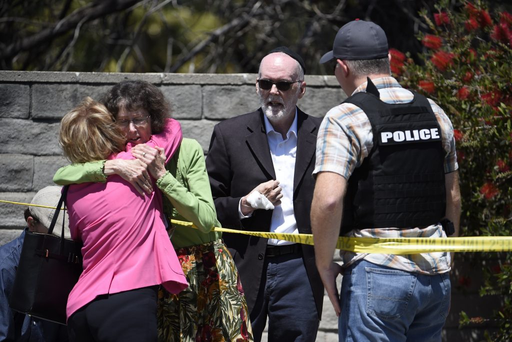 Synagogue Shooting-California Two people hug as another talks to a San Diego County Sheriff's deputy outside of the Chabad of Poway Synagogue Saturday, April 27, 2019, in Poway, Calif. Several people have been shot and injured at a synagogue in San Diego, California, on Saturday, said San Diego County authorities. (Denis Poroy/AP Photo)