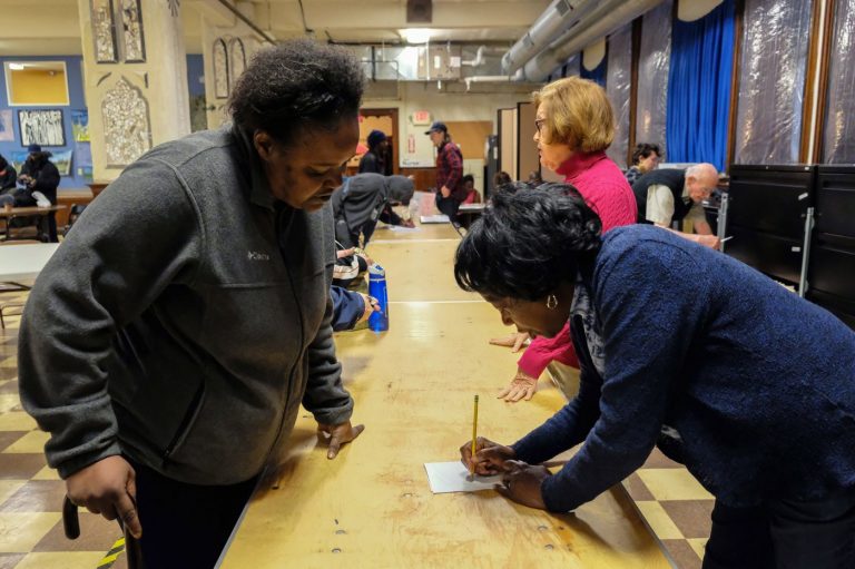 Dee McDowell (left), who is experiencing homelessness, collects her mail from volunteer Chris Martin at Broad Street Ministry on Avenue of the Arts. (Anthony Pezzoti/The Philadelphia Inquirer)