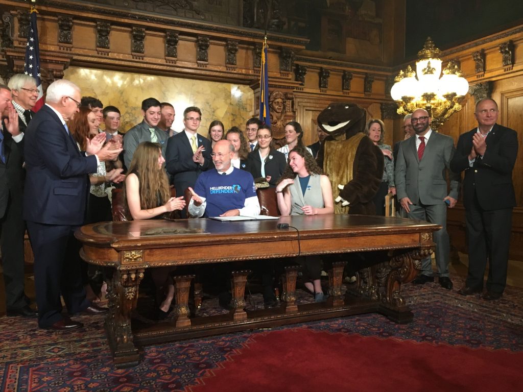 FullSizeRender Surrounded by student supporters of the hellbender — and a mascot — Gov. Tom Wolf signs a bill officially designating the salamander as state amphibian. (Katie Meyer/WITF)