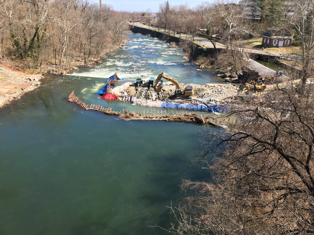 Crews in the middle of the Brandywine River work to remove a 115-year-old dam that was built to allow Wilmington water pipes to cross the river. (Mark Eichmann/WHYY)