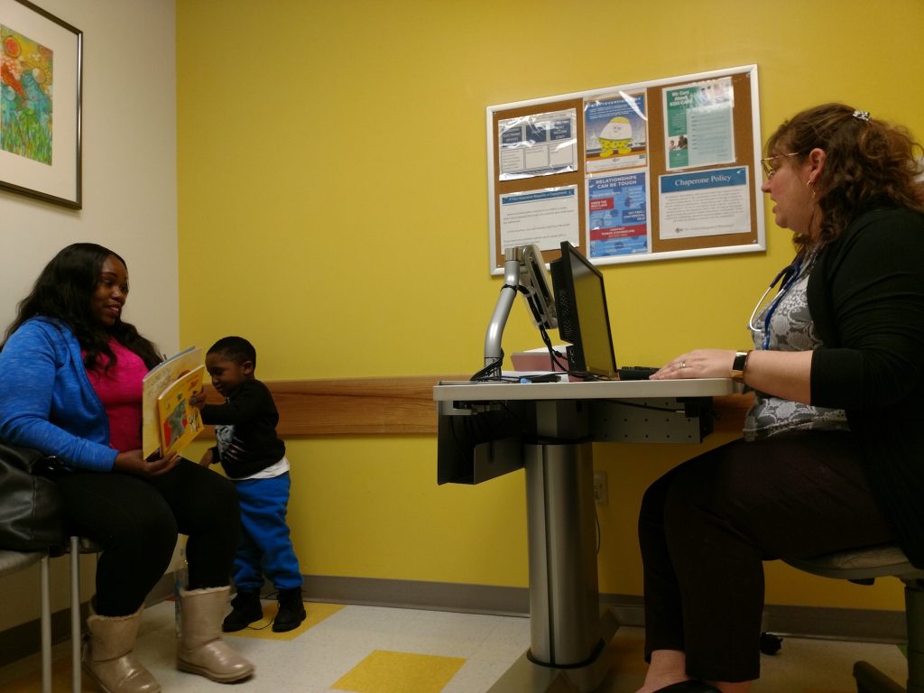 ROR Everly and patient Pediatrician Eileen Everly and mom Teneika Thomas discuss Kyiren Smith's literacy progress during the 4-year-old's visit. Thomas said the boy corrected his teacher when she skipped two pages of a book she was reading in class. (Christine Bahls for WHYY)