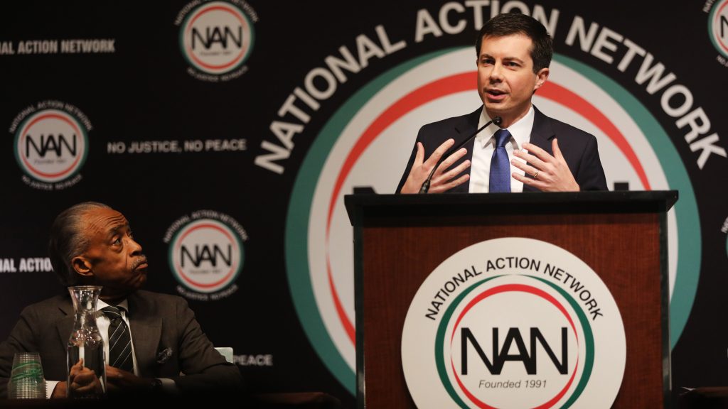 With the Rev. Al Sharpton looking on, Democratic presidential hopeful South Bend, Ind., Mayor Pete Buttigieg speaks at the National Action Network’s annual convention Friday in New York City. With the Rev. Al Sharpton looking on, Democratic presidential hopeful South Bend, Ind., Mayor Pete Buttigieg speaks at the National Action Network's annual convention Friday in New York City. (Spencer Platt/Getty Images)