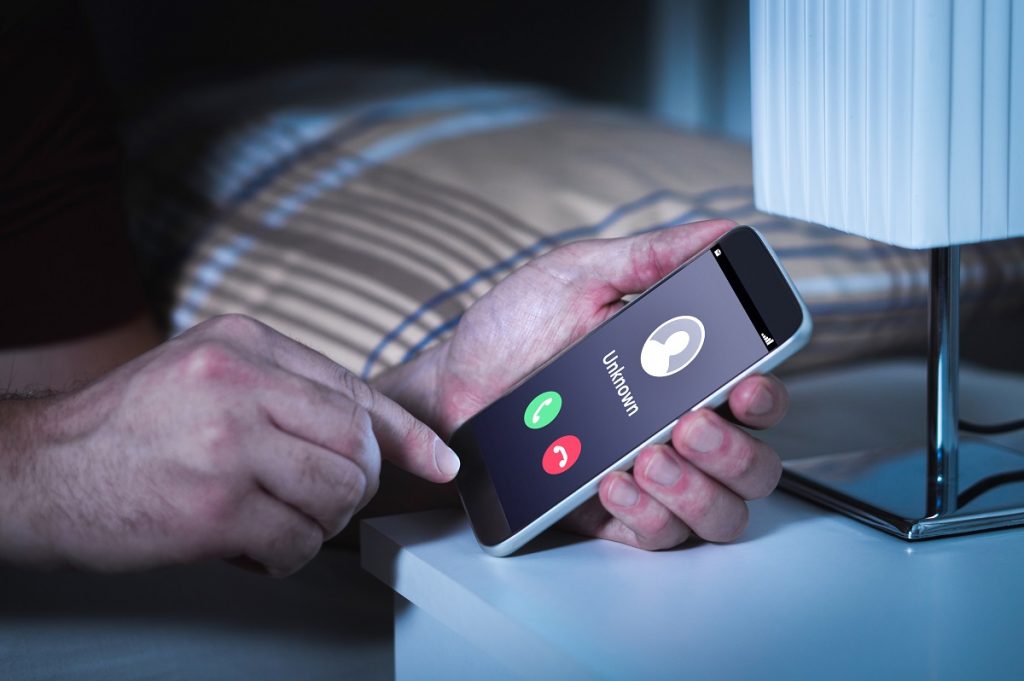 Unknown Number Calling In The Middle Of The Night. Phone Call Fr Unknown number calling in the middle of the night. Phone call from stranger. Person holding mobile and smartphone in bedroom bed home late. Unexpected call woke up.