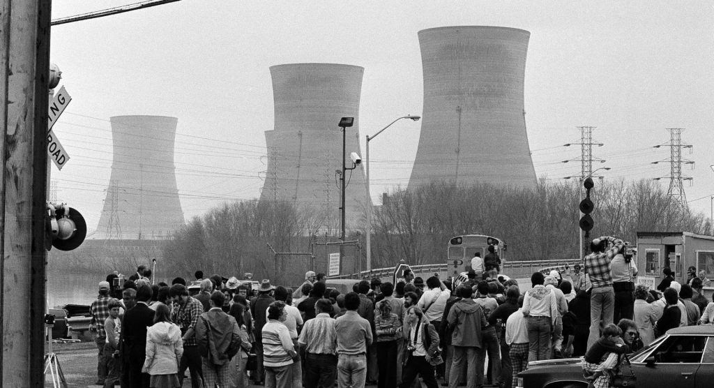 three_mile_island_podcast-e1553713102241-1920×1042 Newsmen and spectators stand in front of the main gate of the Three Mile Island Nuclear Generating Station in Middletown, Penn., April 2, 1979. (Jack Kanthal/The Associated Press)