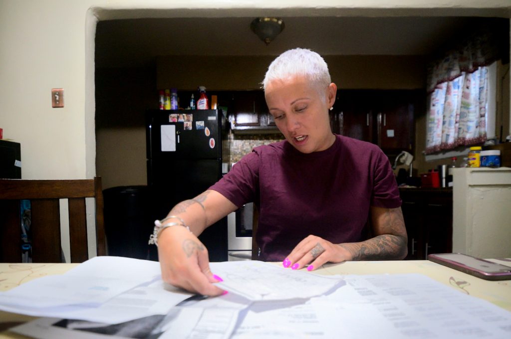 At the kitchen table, Summer Mills goes over documents accumulated in the past months while dealing with dental issues on April 12, 2019. (Bastiaan Slabbers for WHYY)