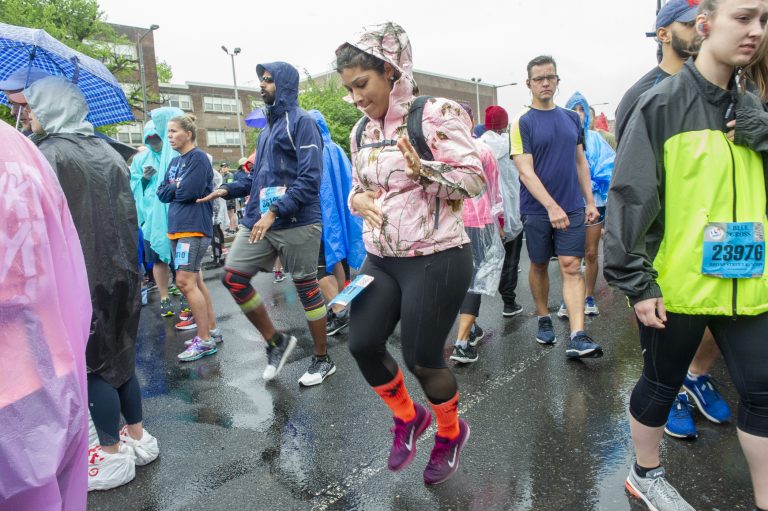 While waiting for the Broad Street Run to begin, Alba Miranda warms up near the Olney Transportation Center. Miranda is a member of the running group Latinas in Motion. (Jonathan Wilson for WHYY)