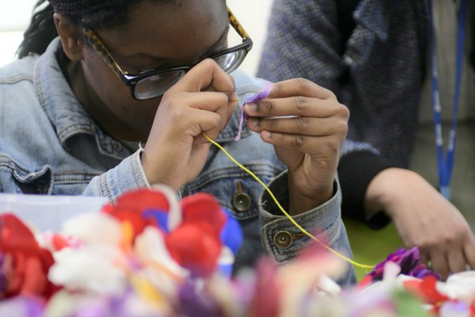 Shamirah Brown, 18, strings together (fake) flowers to be used as decoration for the opening of new horticulture center for students who are blind, visually impaired or have other disabilities at the Overbrook School of the Blind, on Tuesday. (Bastiaan Slabbers for WHYY)