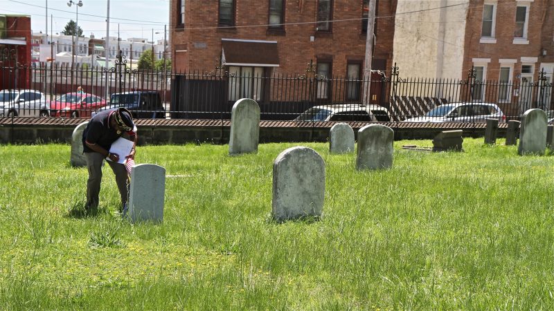 Darryrl Johnson, commander of American Legion Latin American Post 840, checks a list Civil War and Mexican American War veterans buried in St. Anne's Cemetery in order to place American flags on their graves for Memorial Day. (Ximena Conde/WHYY)