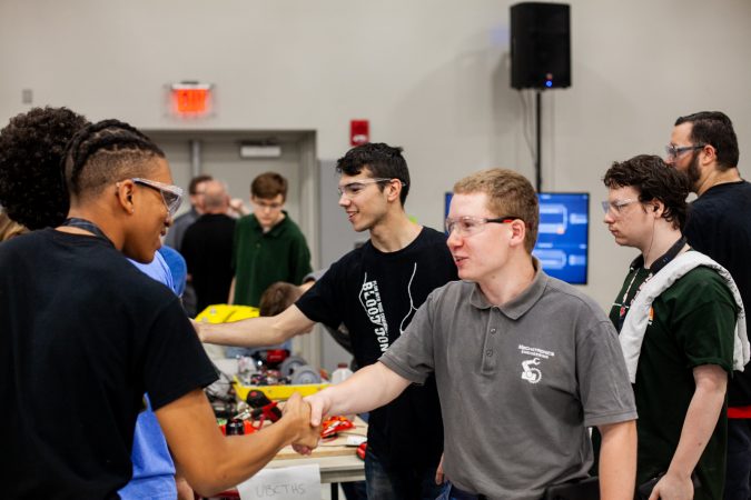 Students from Upper Bucks County Technical School and MaST Community Charter School shake hands after a round of competition in the Liberty Bots competiton Saturday at Montgomery County Community College. (Brad Larrison for WHYY)