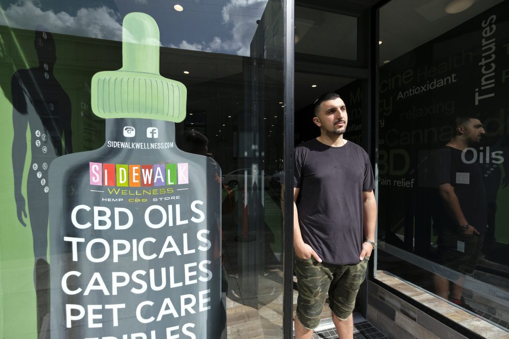 CBD Confusion In this photo taken Thursday, March 21, 2019, Gus Dabais stands outside his Sidewalk Wellness store in San Francisco. CBD oil-infused food, drinks and dietary supplements are popular even though the U.S. government says they're illegal and some local authorities have forced retailers to pull products. The confusion has California, Texas and other states moving to legalize the cannabis compound that many see as beneficial to their health. (Eric Risberg/AP Photo)