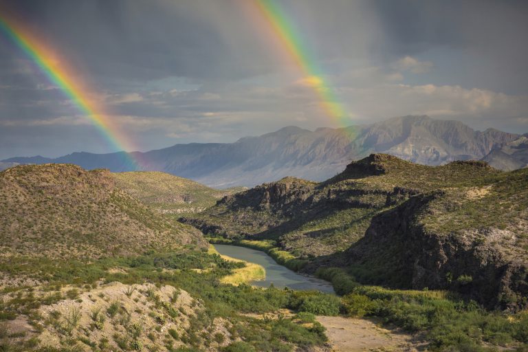 This December, 2017 photo released by Fin and Fur Films shows a double rainbow over Big Bend National Park, Texas, and the Rio Grande along the U.S.-Mexico border, with Mexico being on the right side of the river. The new documentary, 