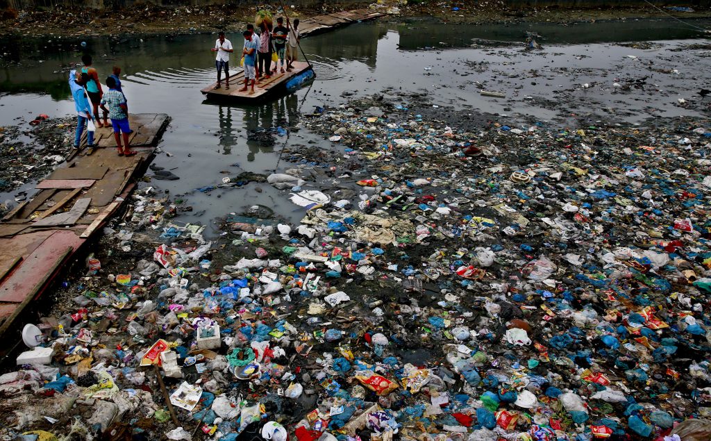UN Environment Plastic Waste In this Sunday, Oct. 2, 2016 file photo, a man guides a raft through a polluted canal littered with plastic bags and other garbage in Mumbai, India. United Nations officials say nearly all of the world's countries have agreed on a deal to better manage plastic waste, with the United States a notable exception. A