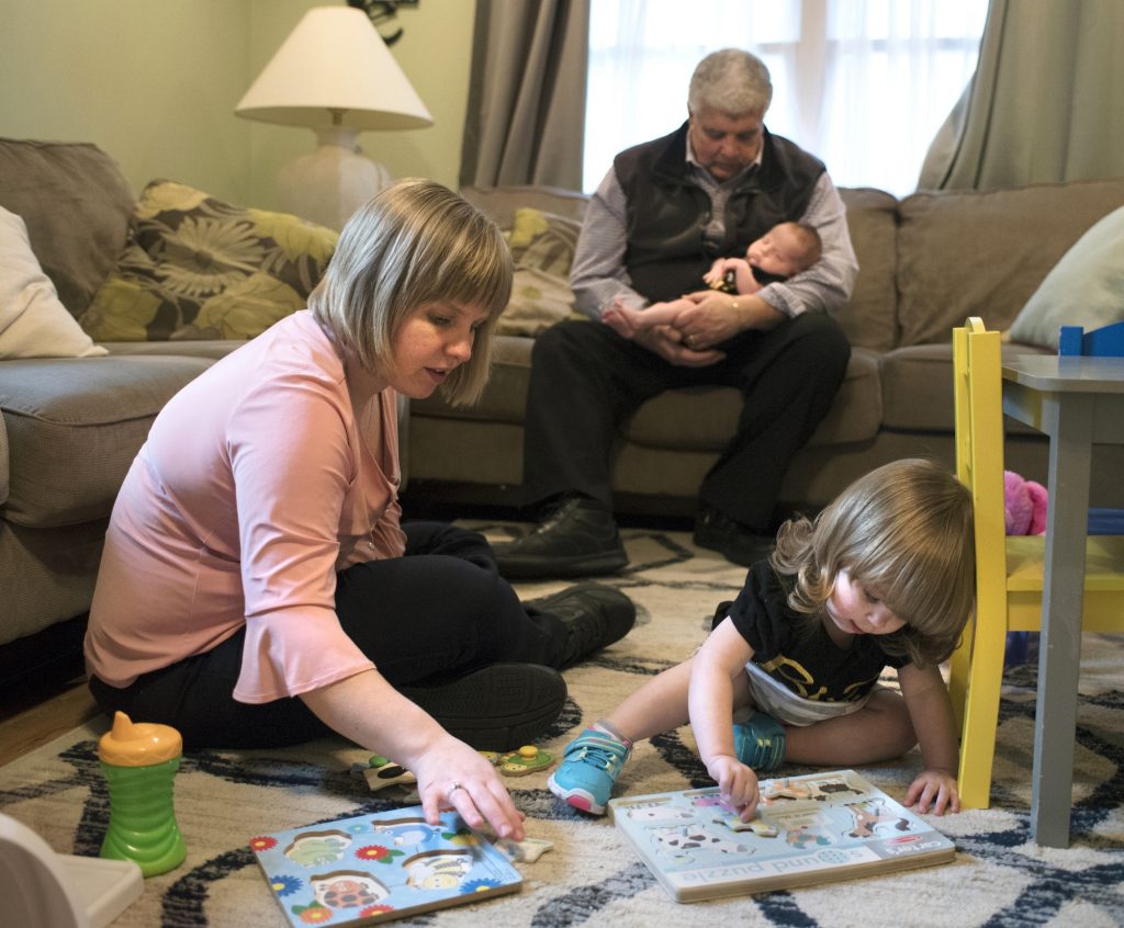 Exchange Brain Injury Motherhood Christina Paravecchia, plays with daughter Madelyn Rose as her dad, Albert “Two-pops” Catarro helps out by holding baby Amelia Grace who was born March 20. Christina had half her brain removed in 1996, when she was eight-years-old. (William Johnson/The Intelligencer via AP)