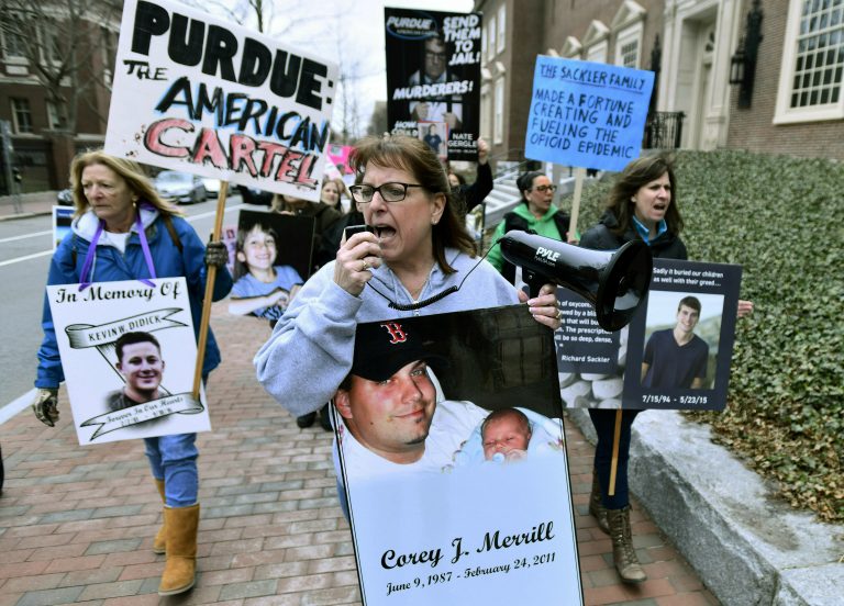 In this Friday, April 12, 2019, file photo, Cheryl Juaire of Marlborough, Mass., (center), leads protesters near the Arthur M. Sackler Museum at Harvard University in Cambridge, Mass. Juaire, whose son was addicted to opioids and died of a heroin overdose in 2011, led the demonstration by parents who’ve lost children in the addiction epidemic. They want the Sackler family name removed from the building at Harvard. In New York, there’s a Sackler Wing at The Metropolitan Museum of Art and a Sackler Center for Arts Education at The Guggenheim. There’s a Sackler Room at the National Gallery in London, a Sackler Wing of Oriental Antiquities at the Louvre. (Josh Reynolds/AP Photo)