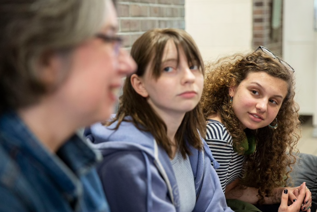 Screen Shot 2019-05-05 at 5.29.54 PM Sasha Mannino (center) and Iris Peron-Ames (right), both 15, look on as Kathryn Gay speaks with them Greenfield Elementary School on Tuesday. Graduates of Greenfield, Mannino and Peron-Ames now attend Science Leadership Academy and are running their second campaign to collect tampons and other toiletries for young people in need. (Heather Khalifa/The Philadelphia Inquirer)