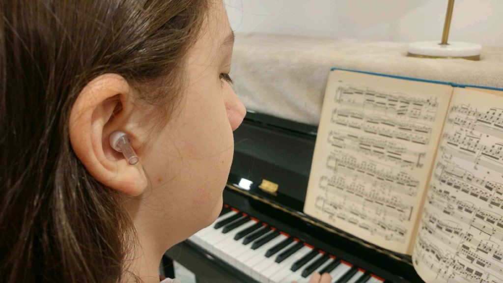 1 Theodore playing piano with ear protection (Daisy James for WHYY)