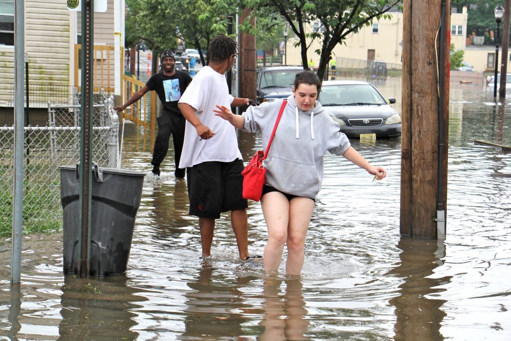 Westville residents (from right) Amberly Lynn, Jay Gray and Lamar Majette, wade through flood waters on Broadway. (Emma Lee/WHYY)