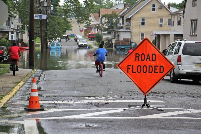 Children on bicycles check out the flooding on High Street in Westville, N.J. (Emma Lee/WHYY)