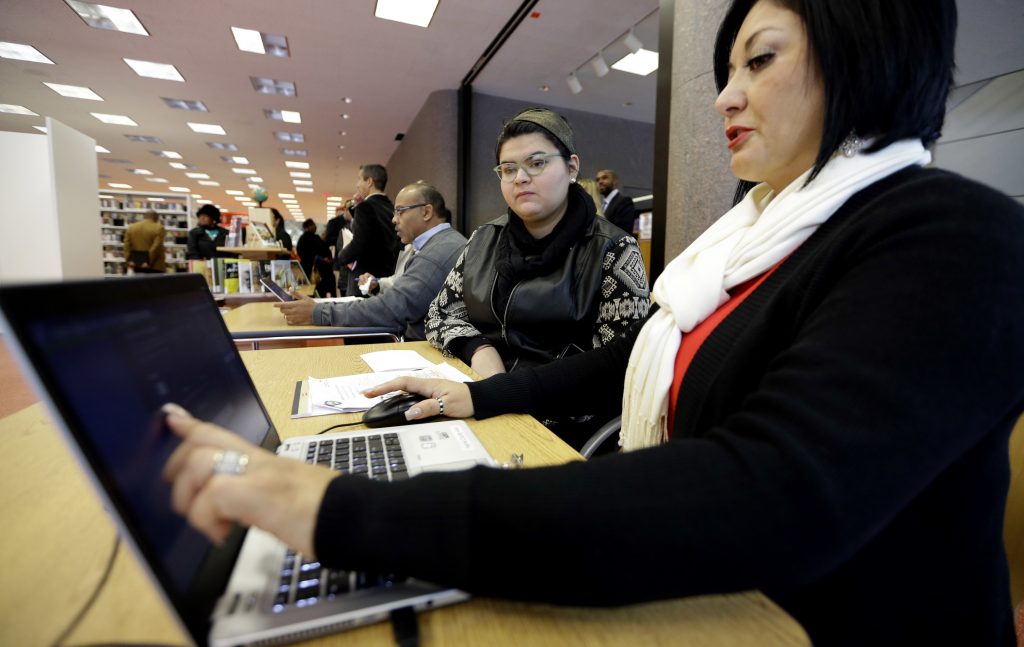 Leticia Chaw, Jennifer Sanchez In this Friday, Nov. 14, 2014 file photo, Affordable Care Act health insurance marketplace navigator Leticia Chaw, right, helps gather information for Jennifer Sanchez to re-enroll in a health insurance plan in Houston. (David J. Phillip/AP Photo)