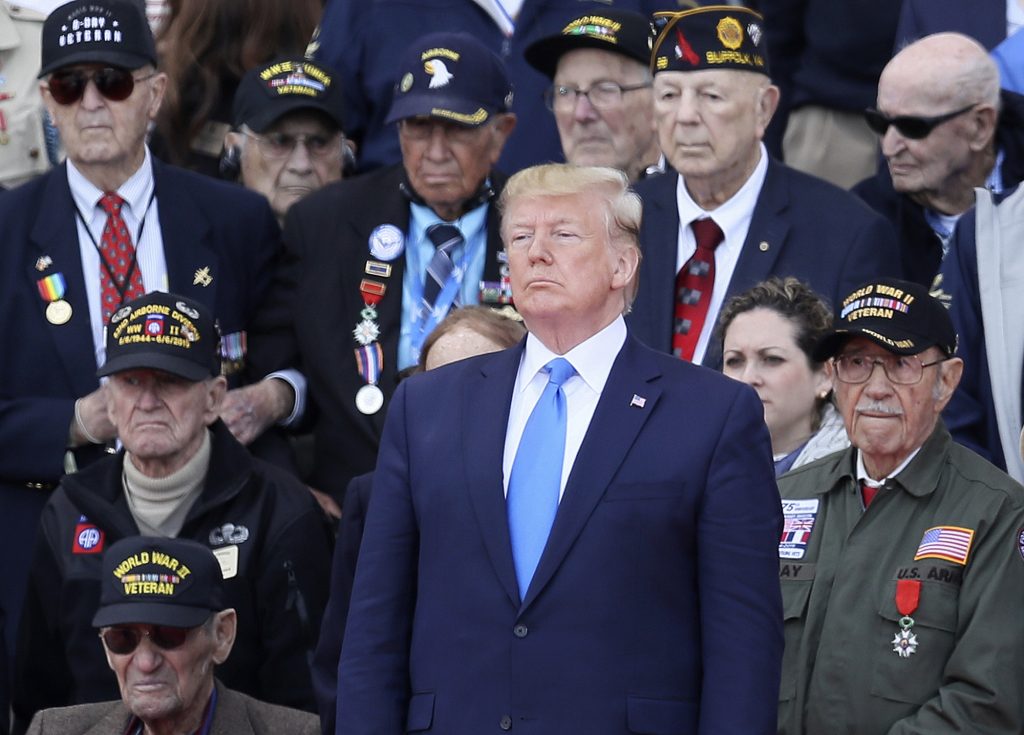U.S. President Donald Trump stands with World War II veterans during a ceremony to mark the 75th anniversary of D-Day at the Normandy American Cemetery in Colleville-sur-Mer, Normandy, France, Thursday, June 6, 2019. World leaders are gathered Thursday in France to mark the 75th anniversary of the D-Day landings. (David Vincent/AP Photo)
