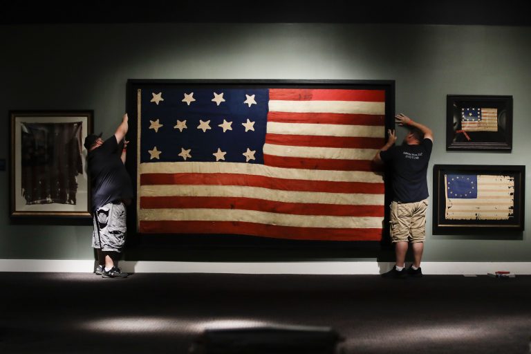 In this Wednesday, June 12, 2019 photo, workmen hang a Federal Era flag as part of the new exhibit 'A New Constellation: A Collection of Historic 13-Star Flags,' at the Museum of the American Revolution in Philadelphia. (Matt Rourke/AP Photo)